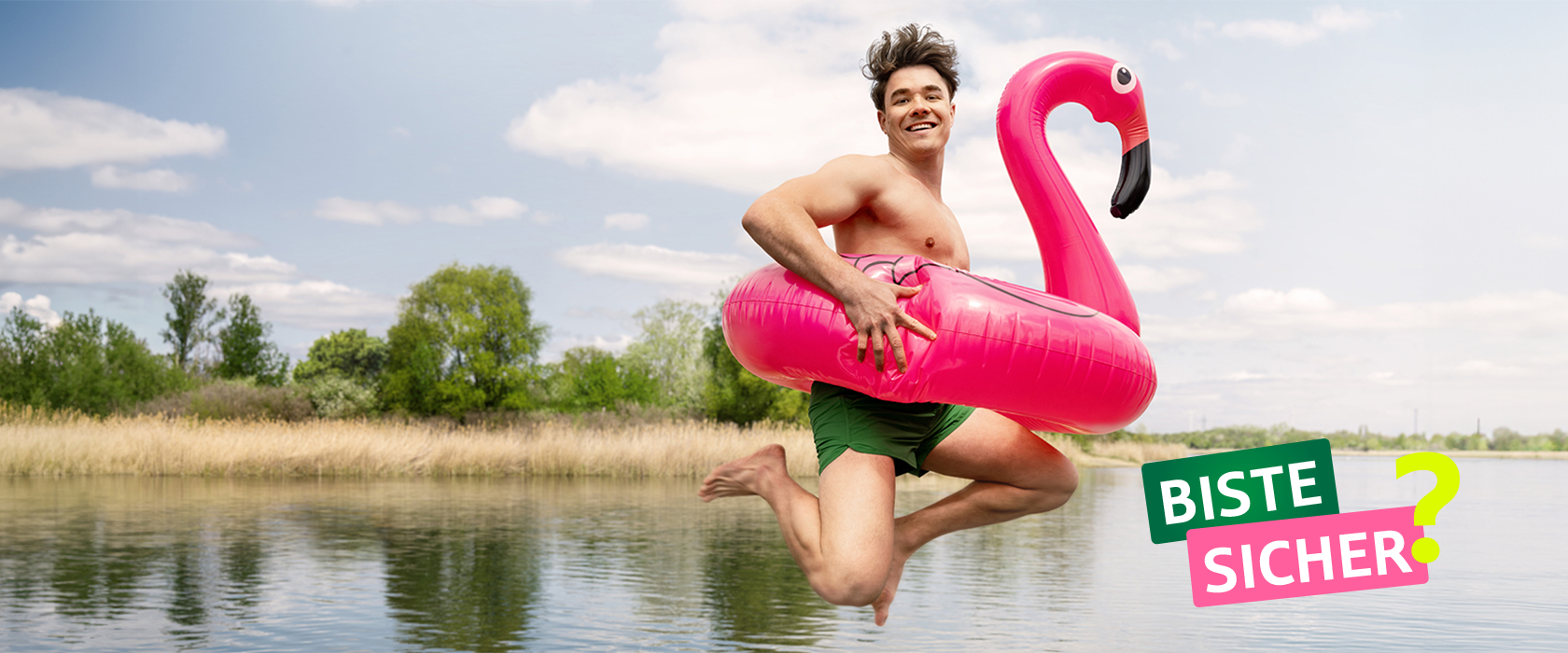 Junger Mann in Badehose springt mit aufblasbarem rosa Flamingo ins Wasser | ÖSA