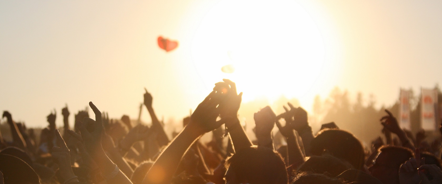 Eine Menschenmenge, die entgegen der Sonne stehend, auf einem Festival jubelt.