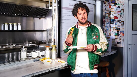 Mann sitzt mit einem Kind am Fenster, beide schauen nach draußen und zeigen aufblickend auf die Natur.