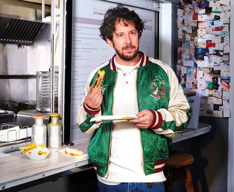 Mann sitzt mit einem Kind am Fenster, beide schauen nach draußen und zeigen aufblickend auf die Natur.