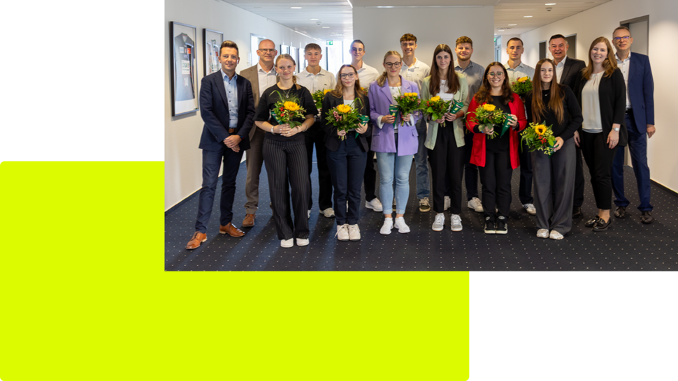 Gruppe von Personen mit Blumengebinden in einem modernen Büroraum, einige stehen, andere sitzen.