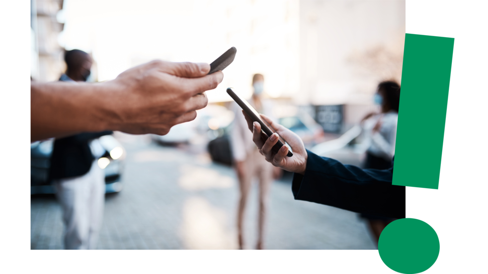 Zwei Personen reichen sich Smartphones über einer Straße; im Hintergrund sind weitere Menschen und Autos sichtbar.